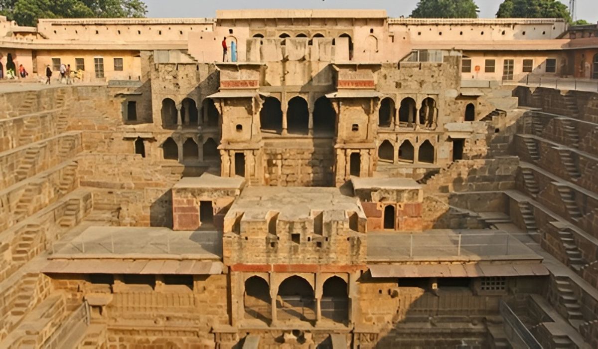 Chand Baori stepwell in Abhaneri with geometric stone staircases and pavilion structures, visited during Golden Triangle India Tours.