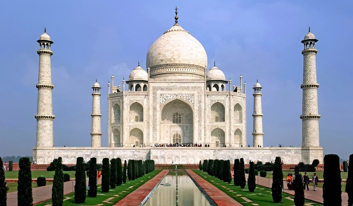 Front view of the Taj Mahal in daylight with reflection pool and visitors, a major stop on the Golden Triangle India Tour.